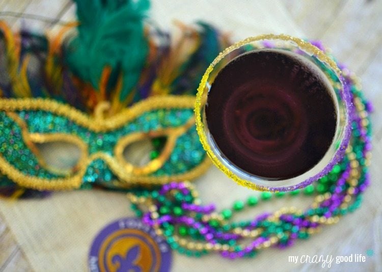 white background with purple martini, Mardi Gras mask and beads on a table
