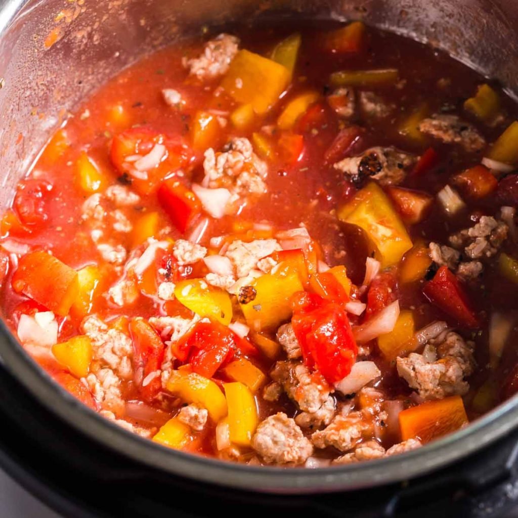 Instant Pot with the lid off, and ingredients inside waiting to be cooked. Tomato sauce, ground turkey, bell peppers and onions, and spices. 