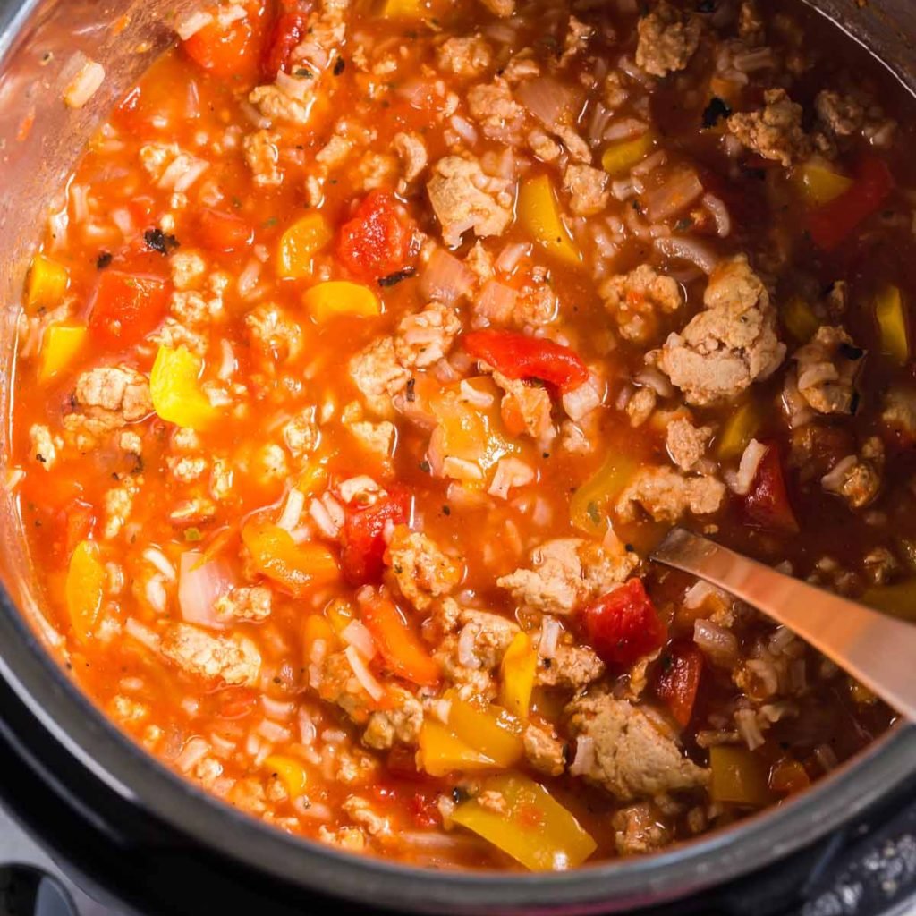 Instant Pot with the lid off, and cooked ingredients inside. Tomato sauce, ground turkey, bell peppers and onions, and spices.