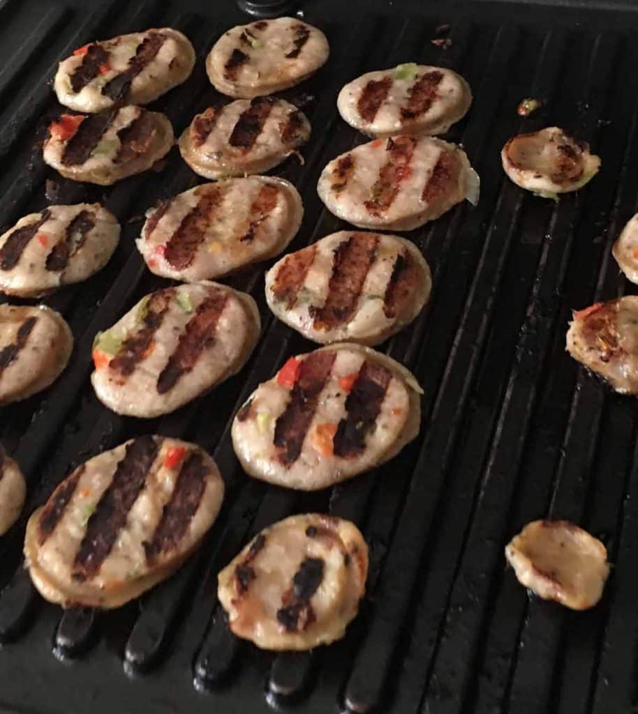 sliced sausage being cooked on a grill