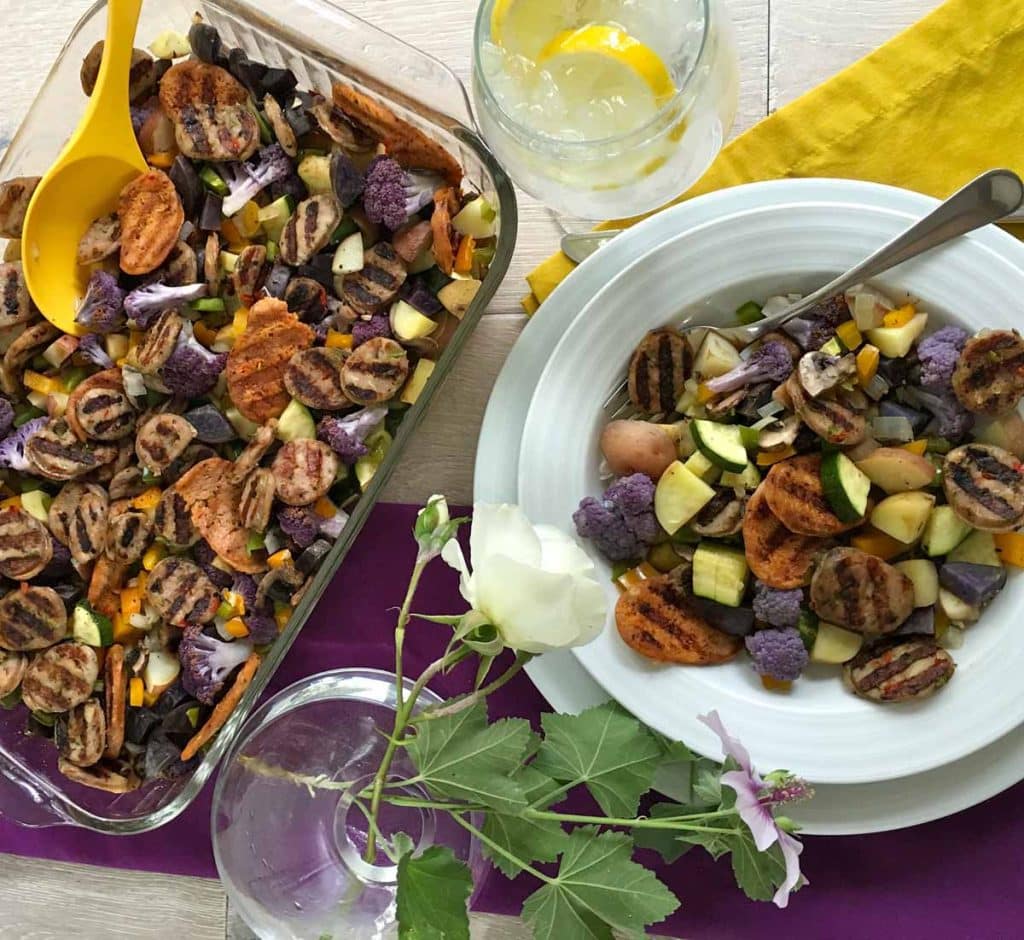 glass baking dish and white bowl filled with cooked sausage and vegetables