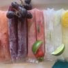 line up of boozy popsicles with fresh fruit garnish on top
