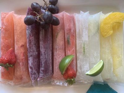 line up of boozy popsicles with fresh fruit garnish on top