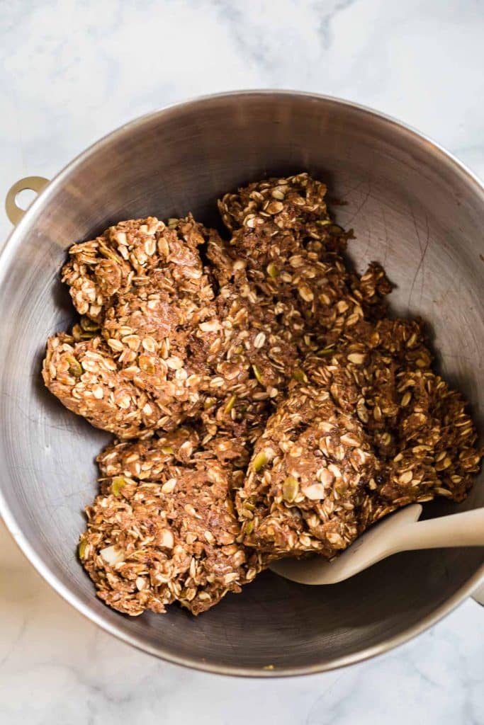 mixing bowl with wooden spoon mixing peanut butter, honey, oats, chocolate chips and other add-ins for granola bars