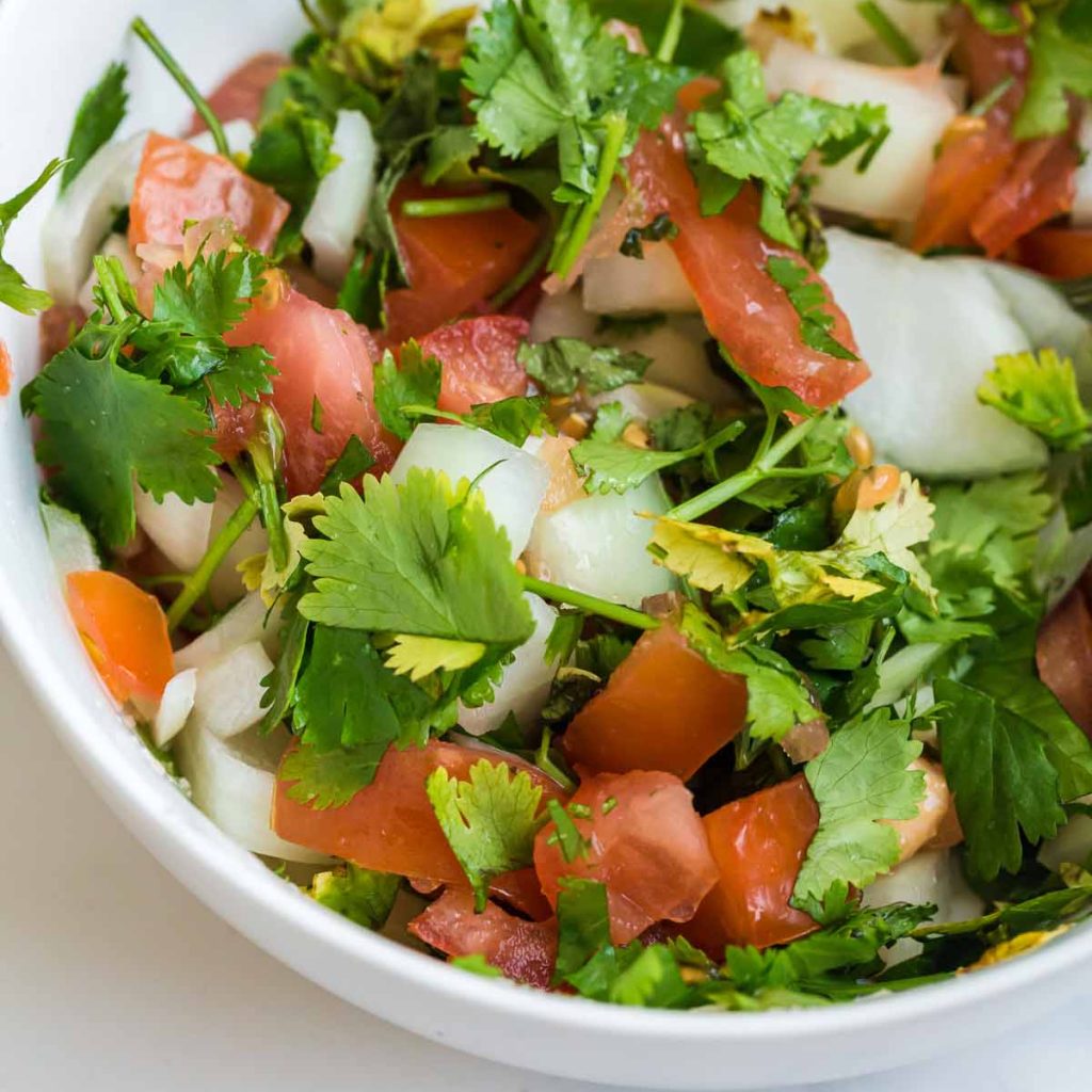 close up view of chopped cilantro, tomatoes, and onion