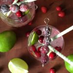 cranberry margarita in a glass with green and white straws