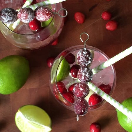 cranberry margarita in a glass with green and white straws