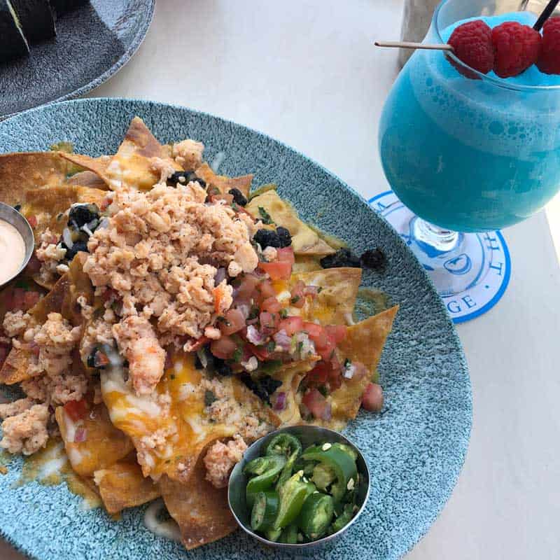 Blue plate full of Lobster Nachos without the cream sauce, festive blue cocktail on the side