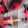 strawberry margarita popsicles on a white wood background