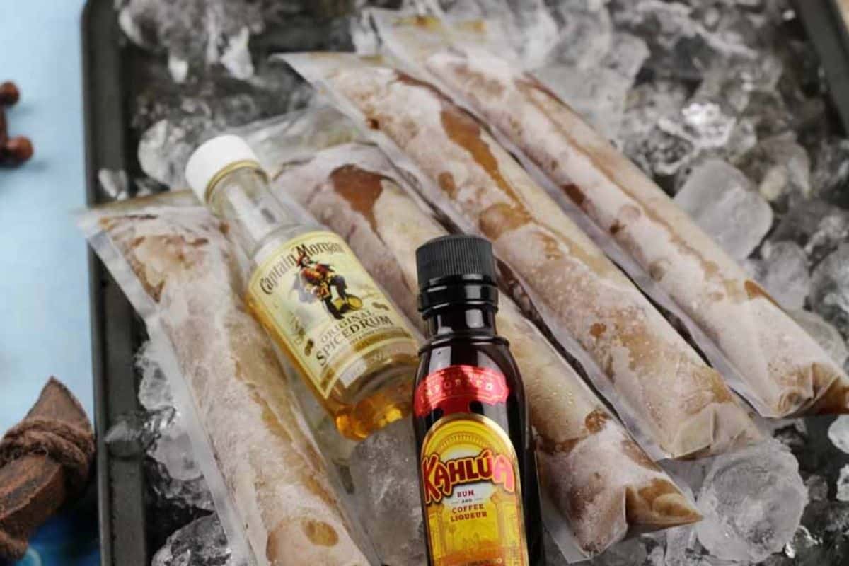 A tray of ice that is topped with dirty pirate popsicles and a couple small bottles of rum and kahlua.