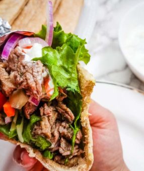 close up of hand holding steak gyro