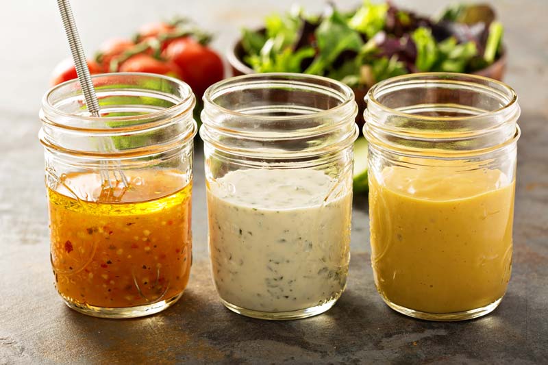 three mason jars with salad dressing
