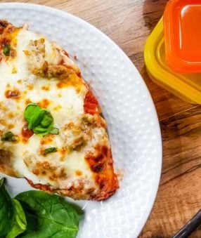 large slice of lasagna on a white plate with 21 day fix containers