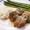swedish meatballs on a white plate with asparagus and potatoes