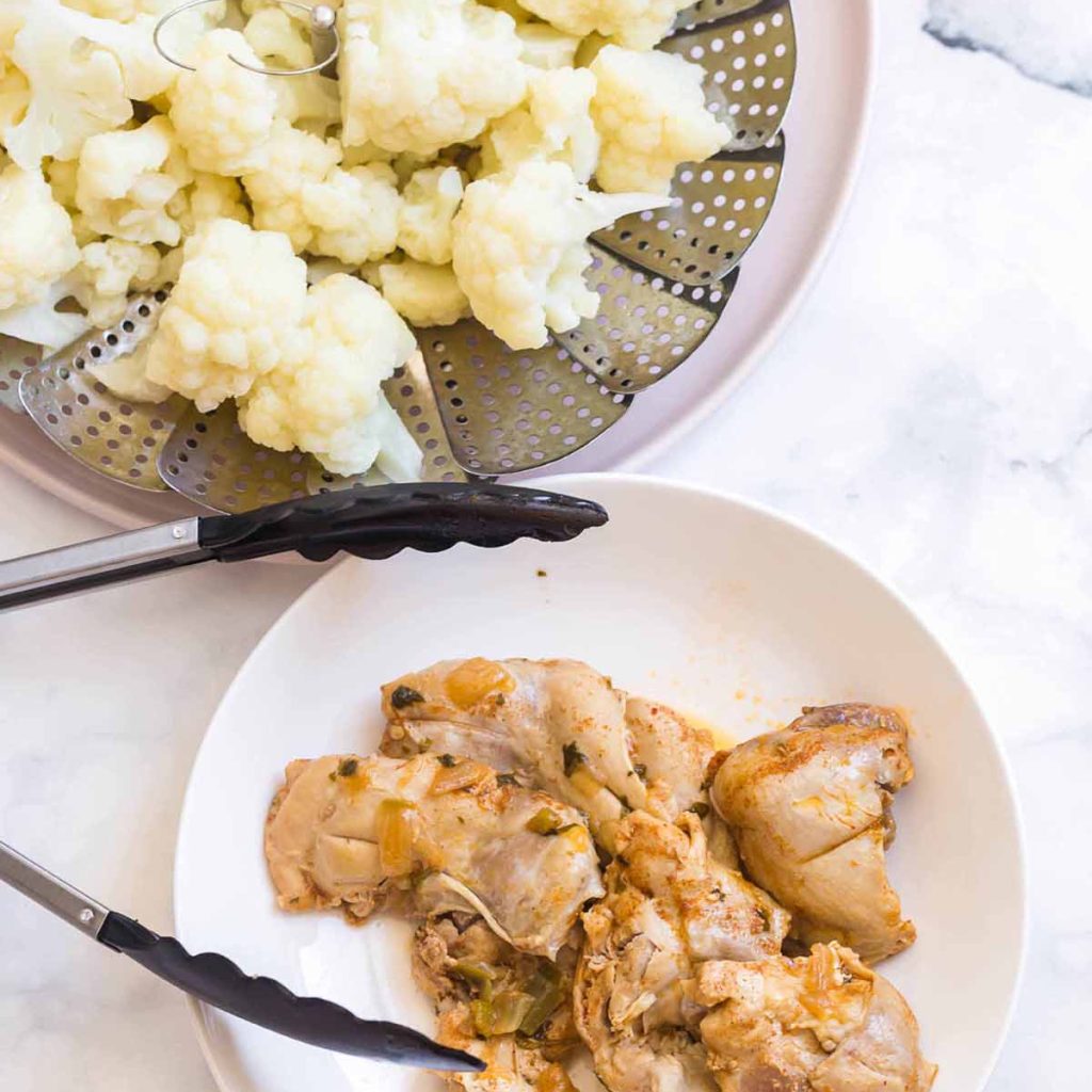 cooked cauliflower and cooked chicken thighs on a white counter