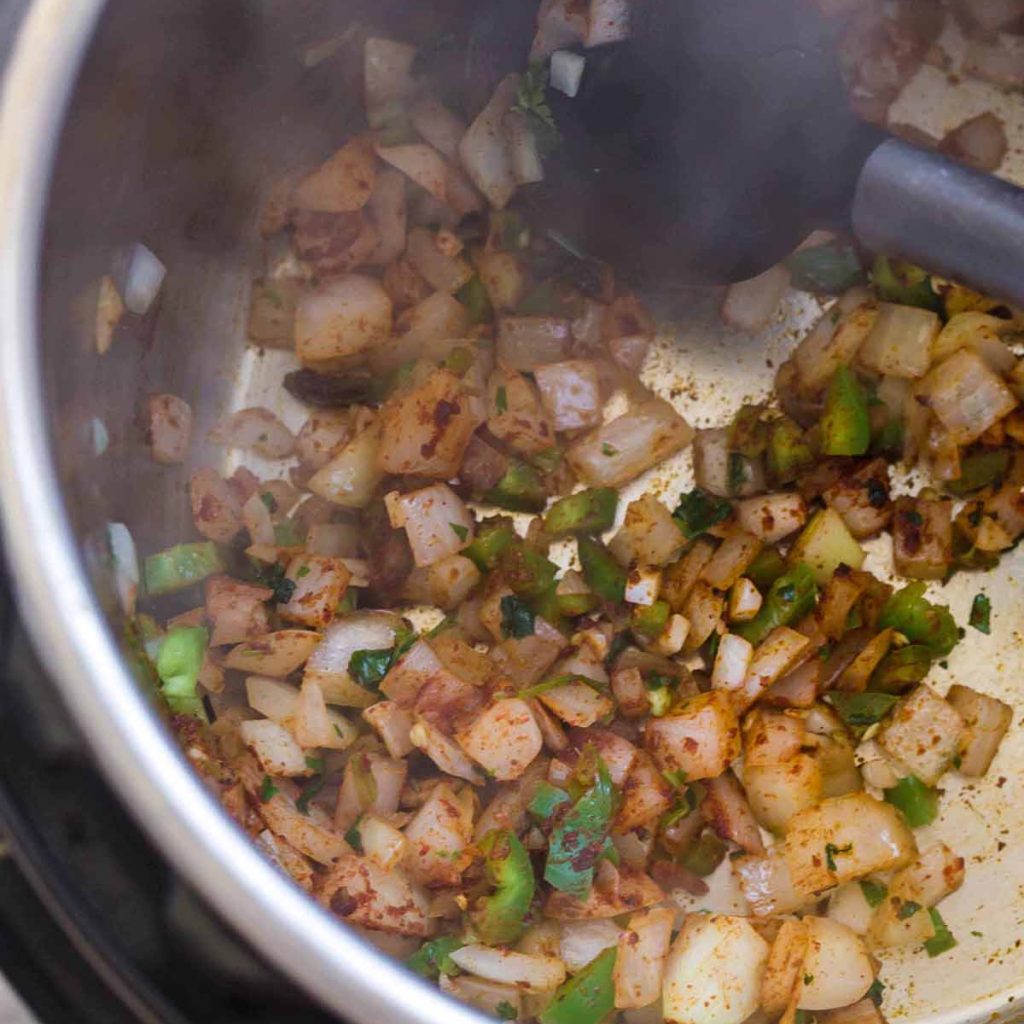 top down view of Instant Pot with onions, cilantro, and jalapeños cooking with spices
