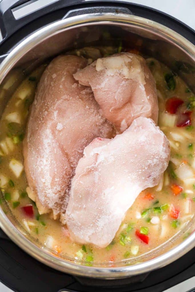 instant pot with frozen chicken breasts and other ingredients needed to make White Chicken Chili