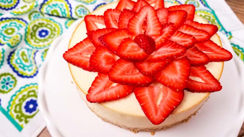 cheesecake with sliced strawberries on a white platter