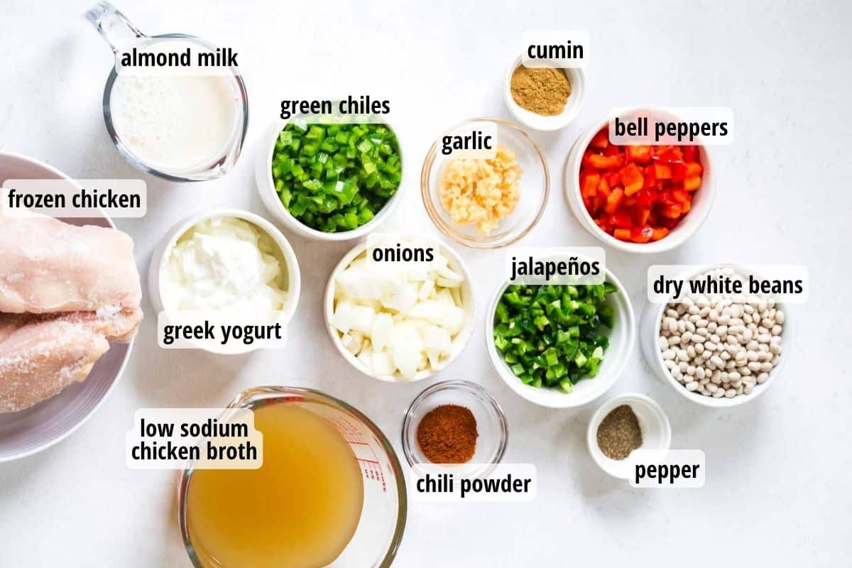 A white countertop with bowls and plates of labeled ingredients needed to make Weight Watchers white chicken chili.