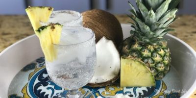 pineapple slice, coconut slice, and two pina coladas on a tray