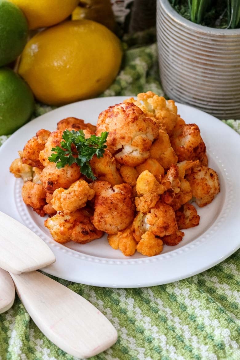 buffalo cauliflower on a white plate with green background