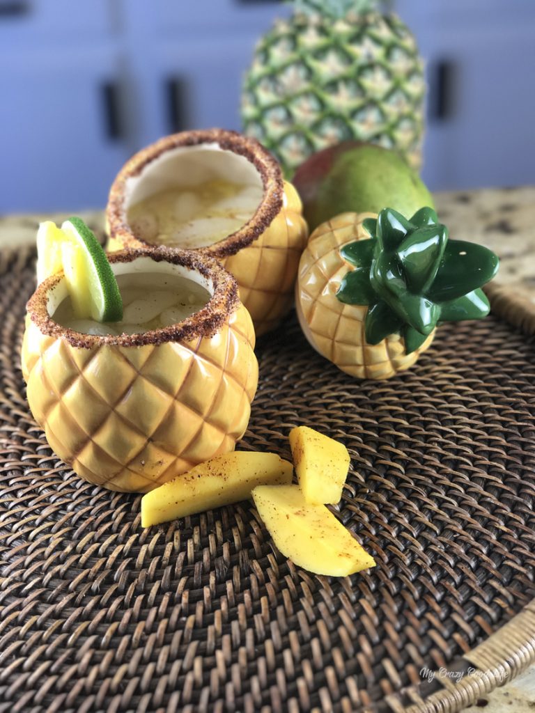 pineapple cups filled with margarita on a woven platter