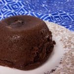 small chocolate cake on a plate with blue towel in background