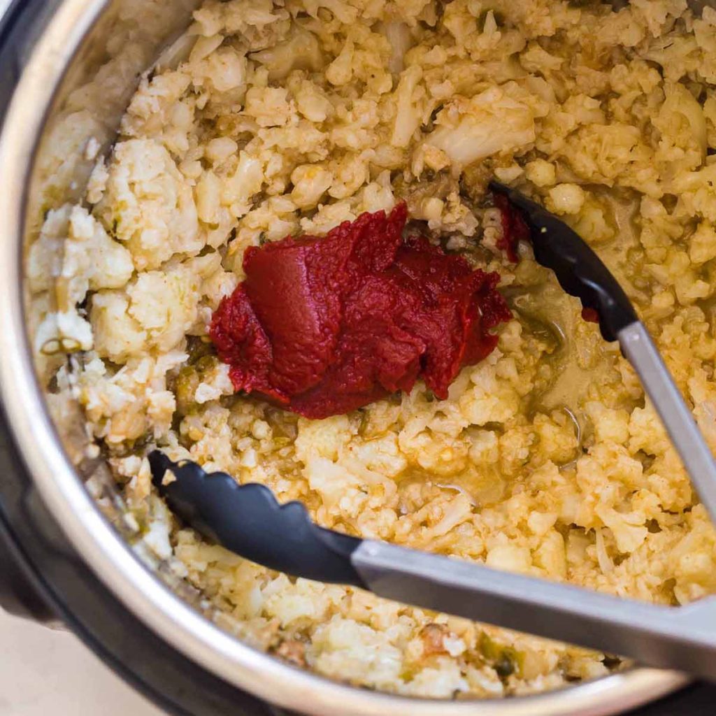 riced cauliflower with tomato paste being mixed in
