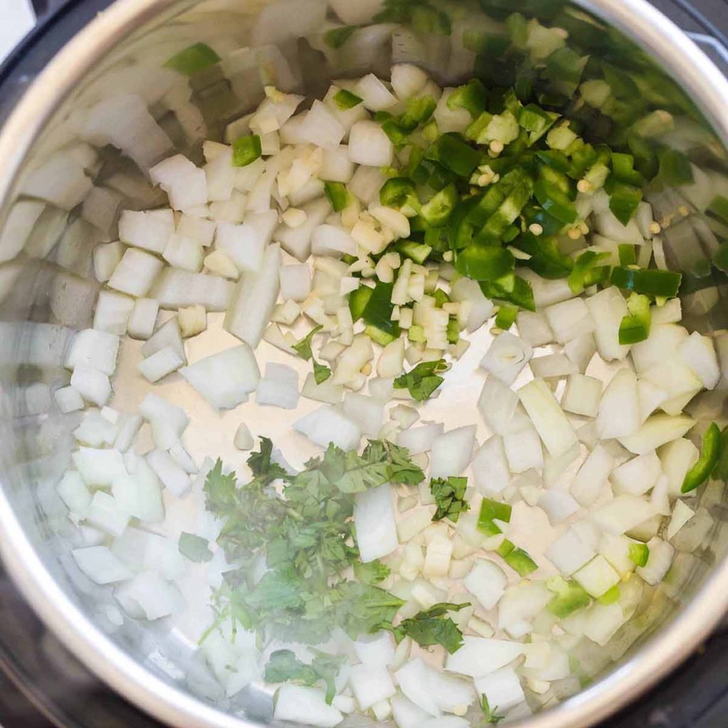 top down view of Instant Pot with onions, cilantro, and jalapeños cooking 