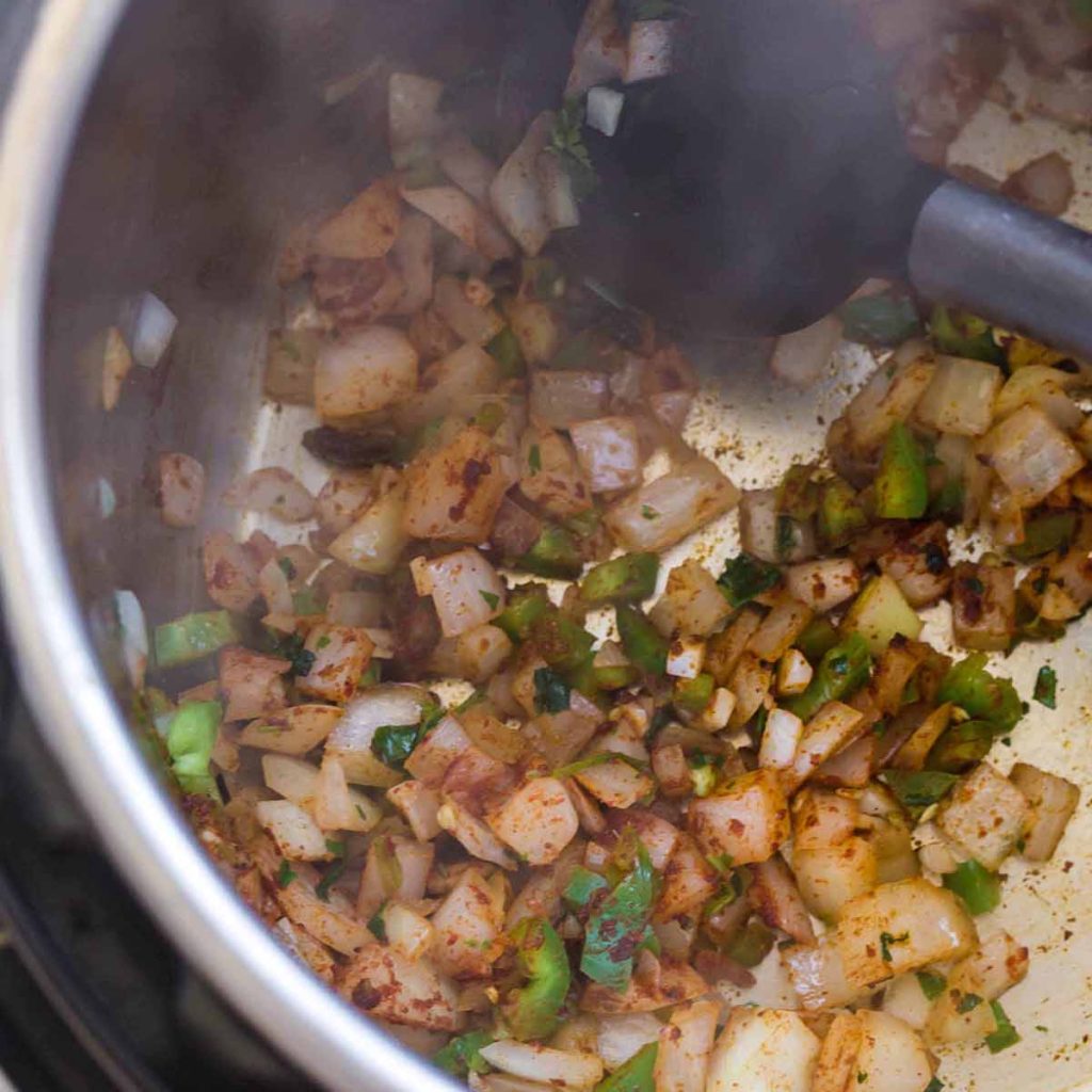 top down view of Instant Pot with onions, cilantro, and jalapeños cooking with spices