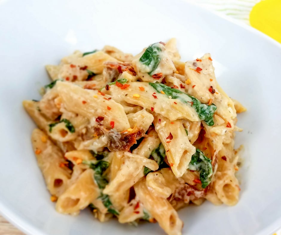 tuscan chicken pasta completed in a white bowl.