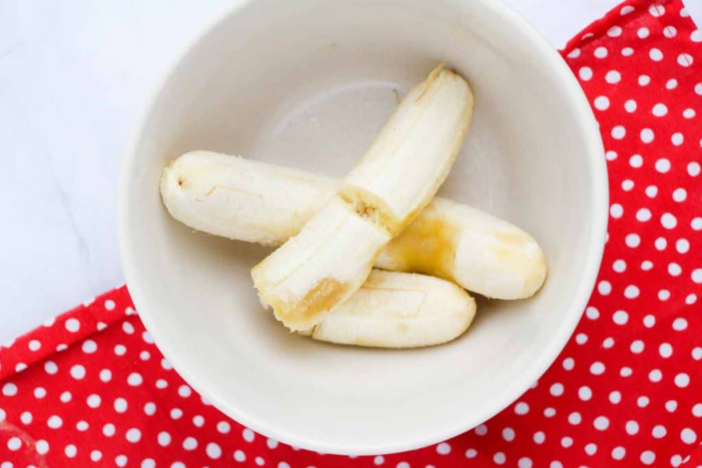 bananas in a white bowl with a red and white polka dot towel underneath