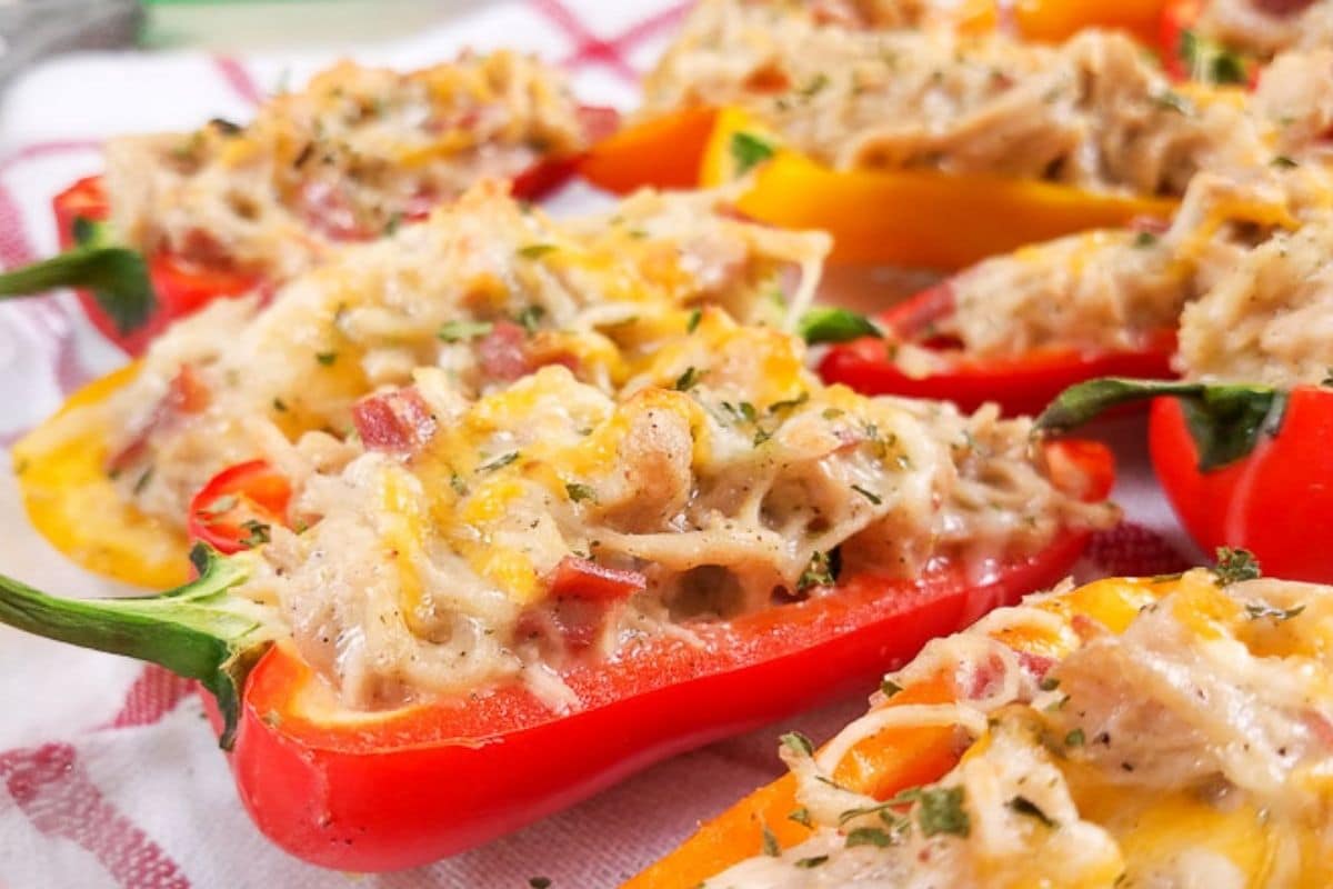 Multi-colored mini peppers cut in half and stuffed with crack chicken and topped with melted cheese.