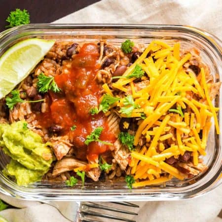 Weight Watchers Burrito Bowl in a glass meal prep container. The bowl is garnished with a wedge of lime, guacamole, cheese and salsa.