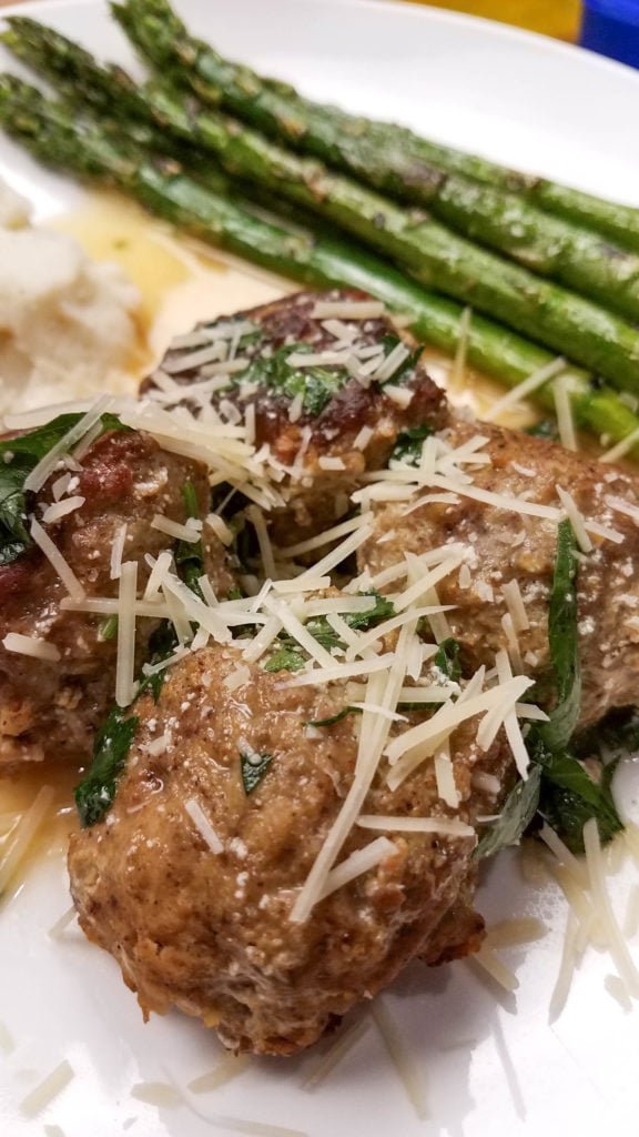 vertical image of meatballs with parmesean cheese on white plate