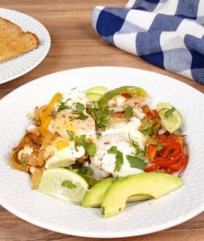 white plate with eggs and veggies, toast in background