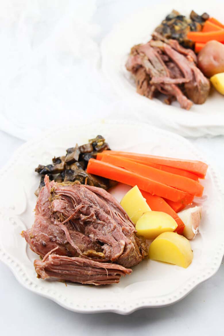 pot roast and carrots and potatoes on a white plate