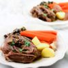 pot roast with carrots and potatoes on white plate