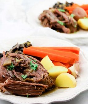 pot roast with carrots and potatoes on white plate