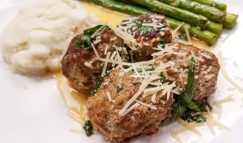 swedish meatballs with asparagus on a white plate