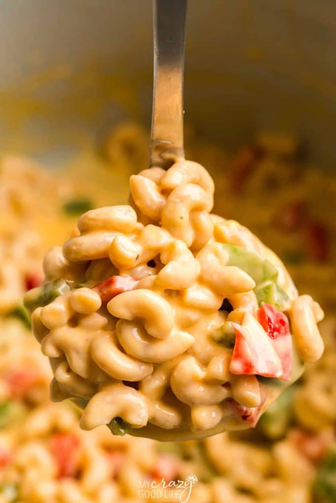 Cooked WW Mac and Cheese with red and green bell peppers on a large serving spoon. 