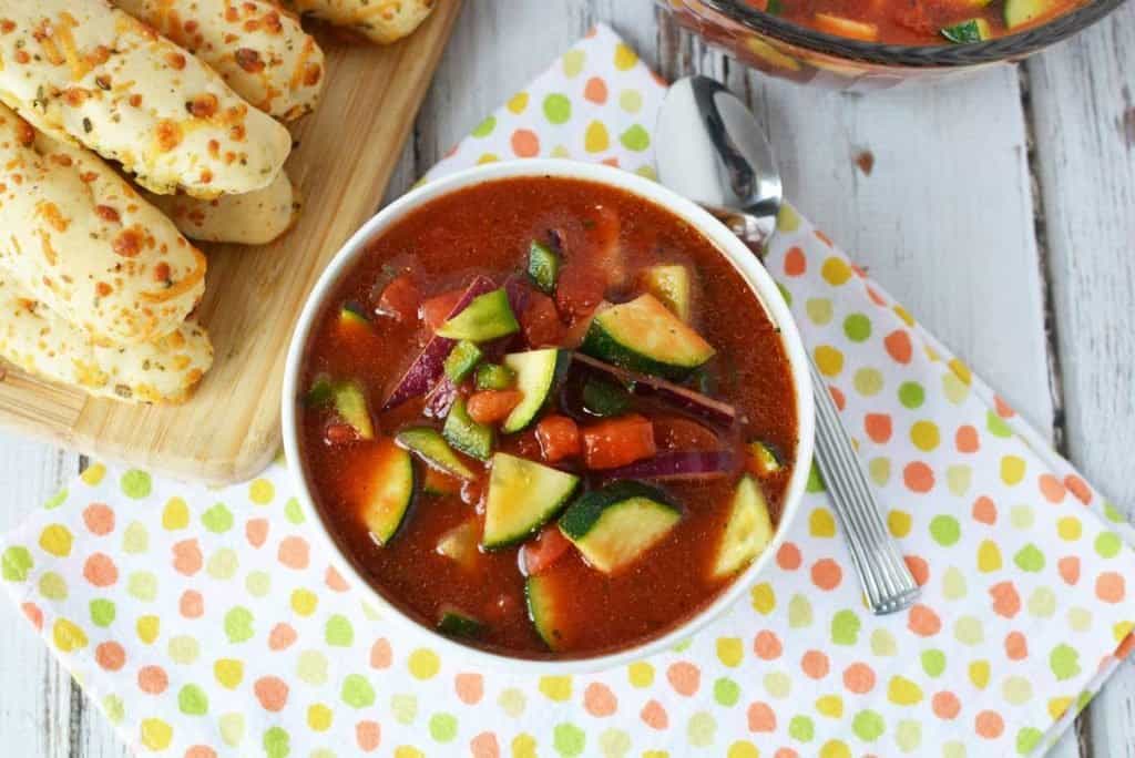 gazpacho soup in white bowl with breadsticks