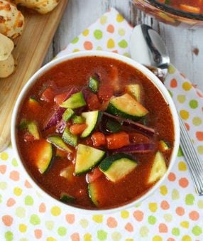 gazpacho soup in white bowl with breadsticks