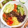 white bowl filled with steak fajitas and fresh toppings