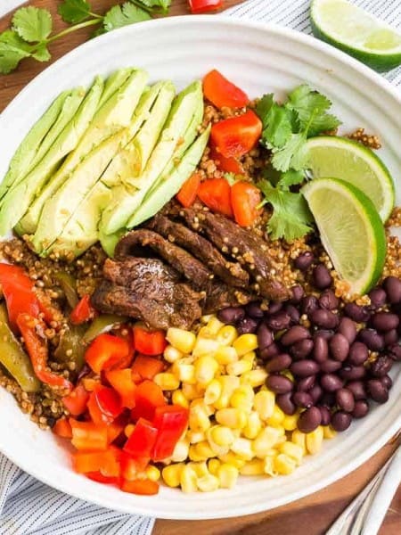 white bowl filled with steak fajitas and fresh toppings