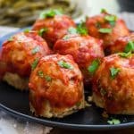 image of mini turkey meatloaves topped with tomato sauce on a black plate