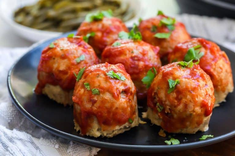 image of mini turkey meatloaves topped with tomato sauce on a black plate