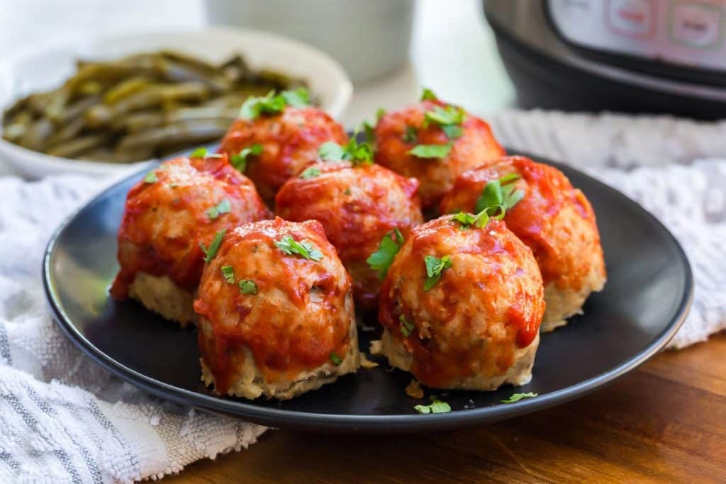 image of mini turkey meatloaves topped with tomato sauce on a black plate