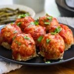 image of mini turkey meatloaves topped with tomato sauce on a black plate