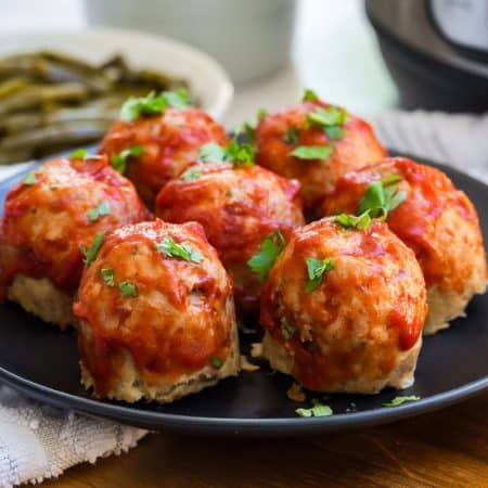 image of mini turkey meatloaves topped with tomato sauce on a black plate